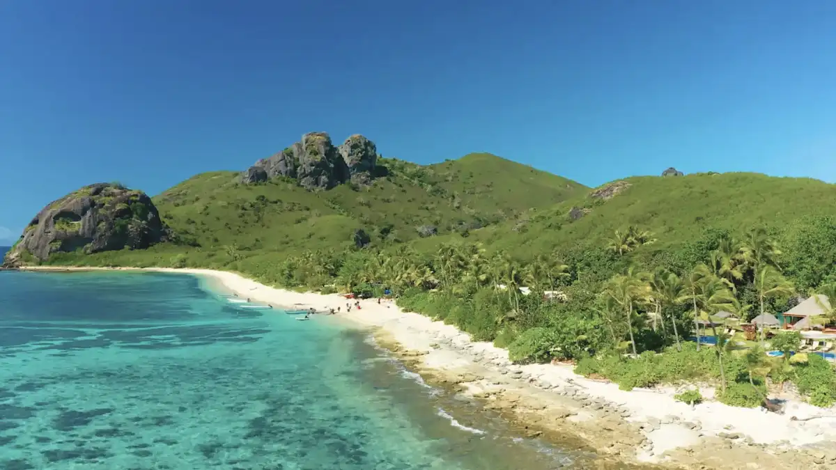 Palm-lined white-sand beach beside clear blue water in Fiji