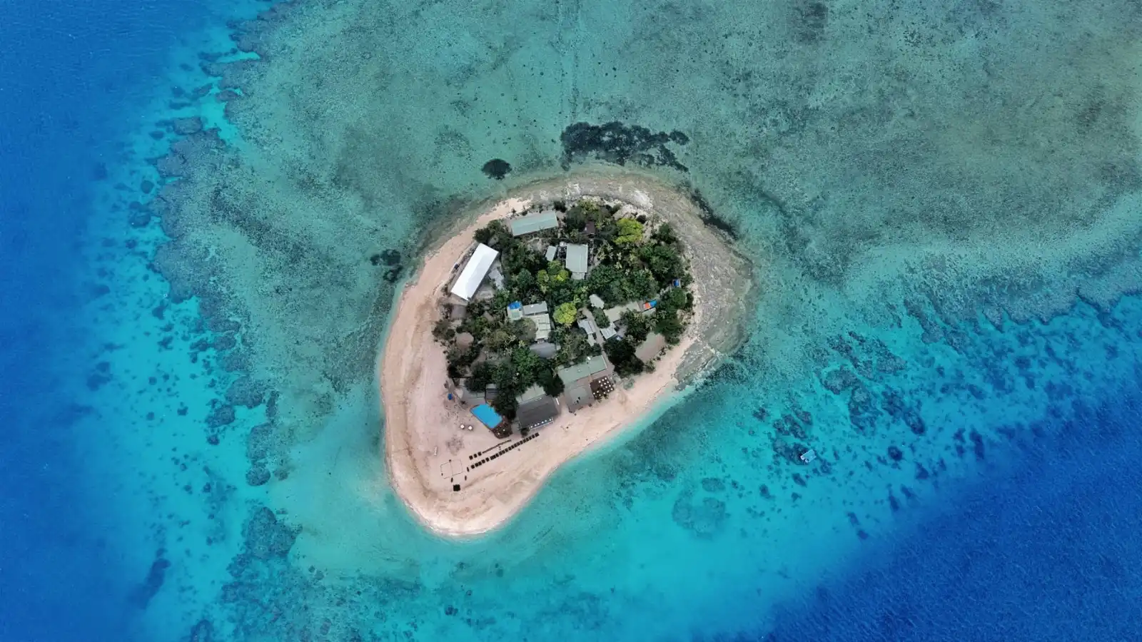 Aerial view of Beachcomber Island in Fiji, with resort buildings, a sandy shoreline and turquoise reef waters