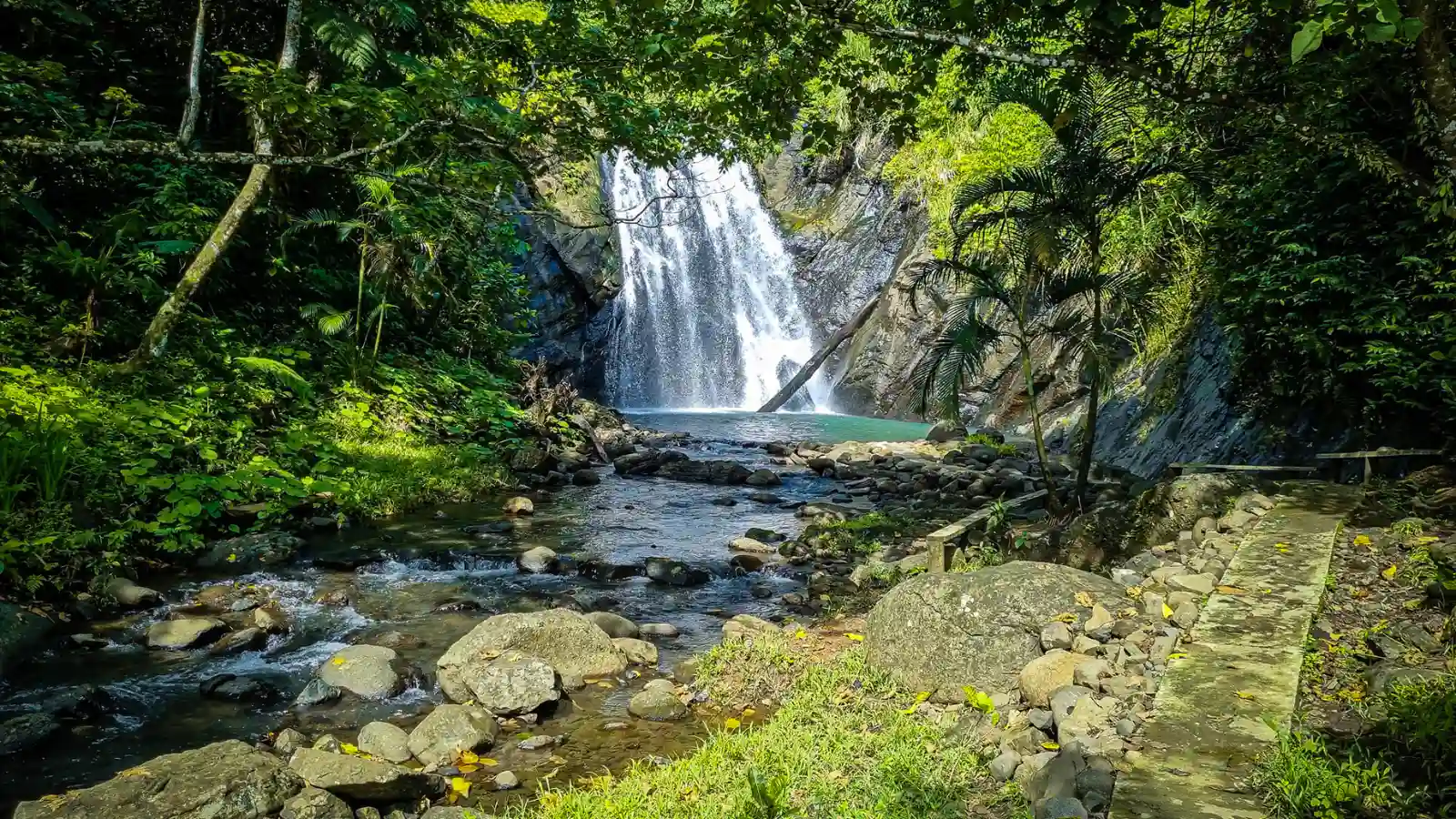 Remote pristine waterfall cascading into turquoise pool surrounded by untouched tropical rainforest and secluded beach in undiscovered Fiji location off the beaten path
