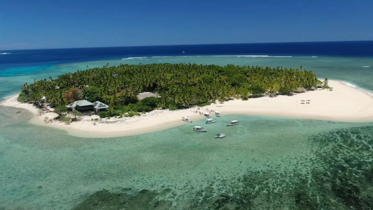 Aerial view of a tropical Fiji island surrounded by a turquoise lagoon and coral reef