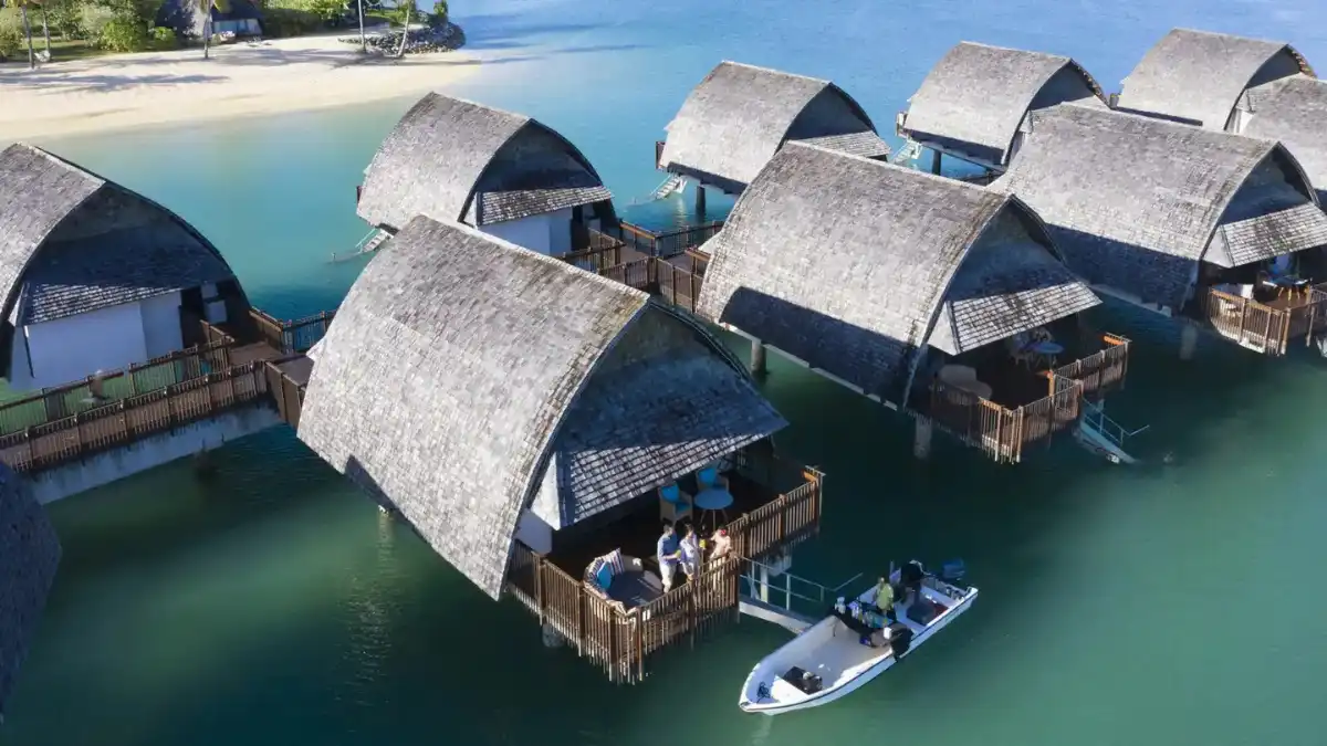 Overwater bungalow above a turquoise lagoon at sunset in Fiji
