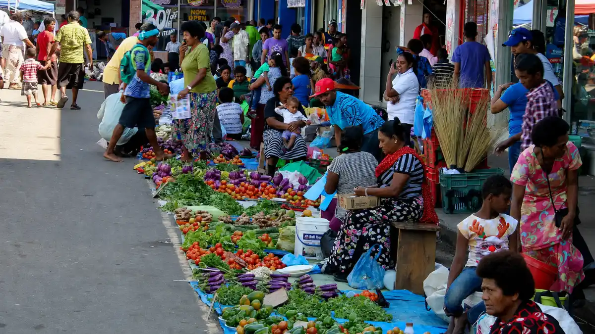 Produce vendors and shoppers beside rows of tomatoes, eggplants, greens and peppers at Sigatoka Market