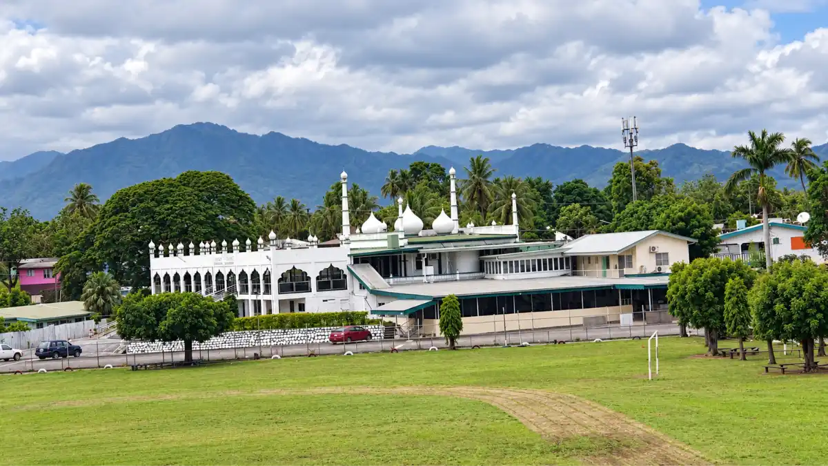 Nadi Jame Masjid in Fiji, viewed across a playing field with mountains behind it