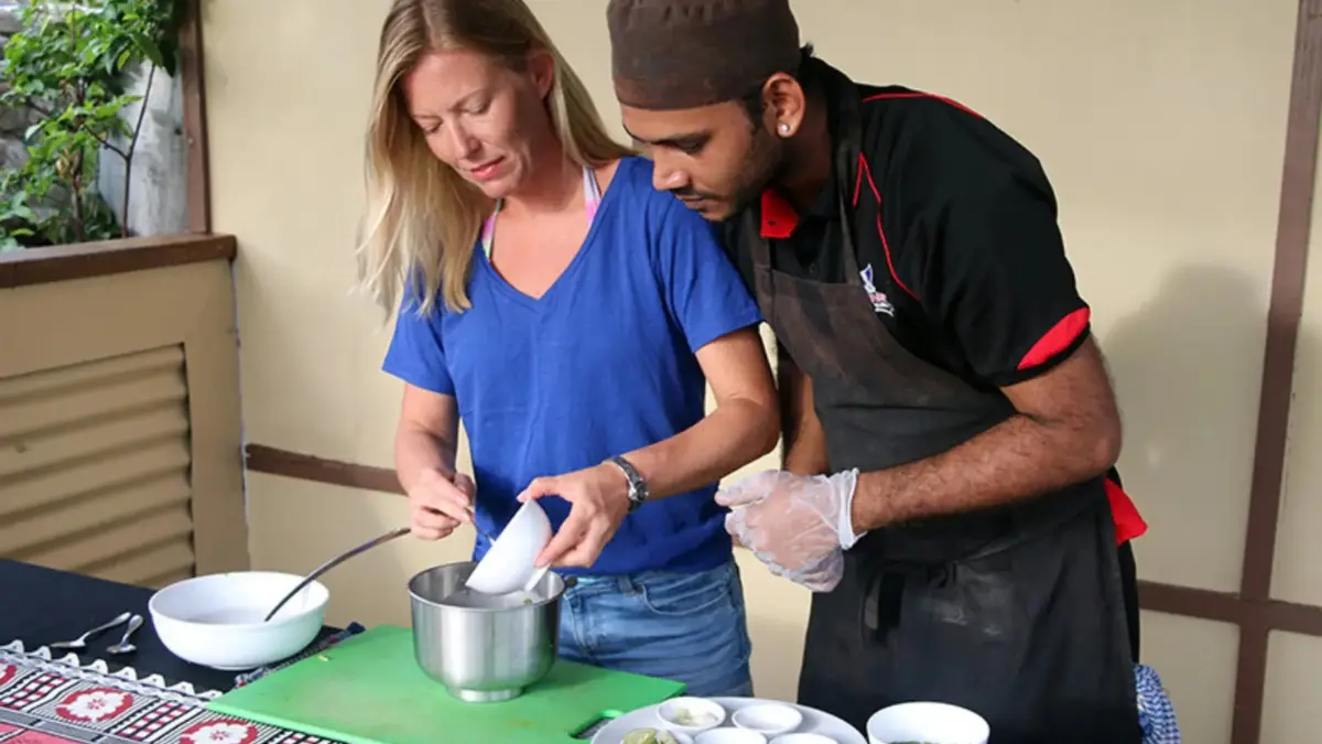 Visitor and cooking instructor preparing food together at a cooking station