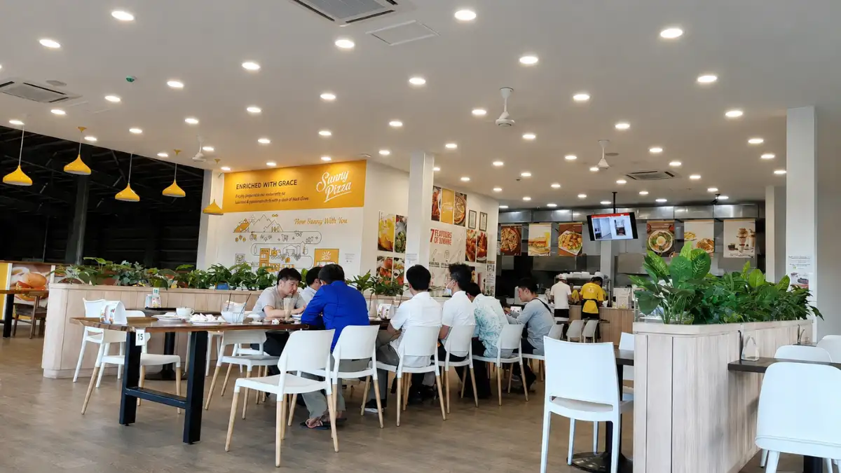 Bright Grace Kitchen and Sunny Pizza dining room in Nadi with white chairs, indoor plants and a pizza counter.