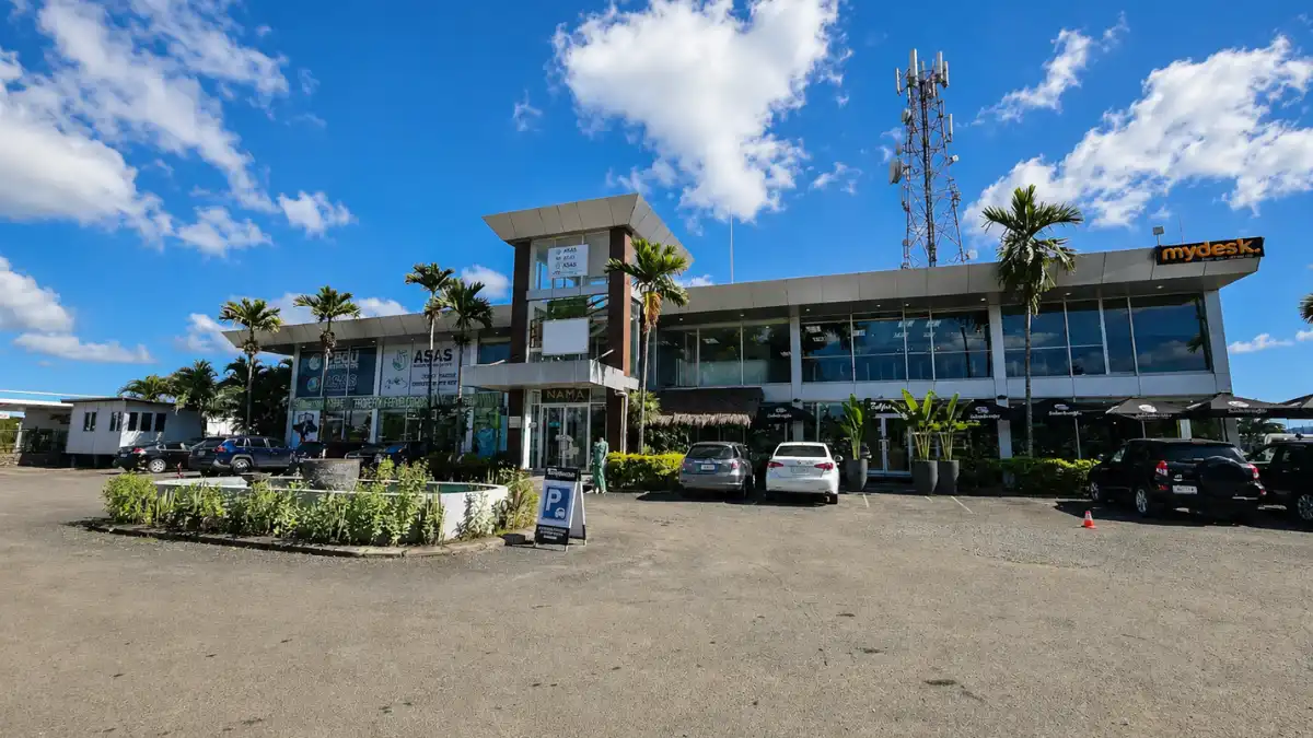 Building housing The Coffee Hub on Nadi Back Road, with outdoor coffee umbrellas and parking.