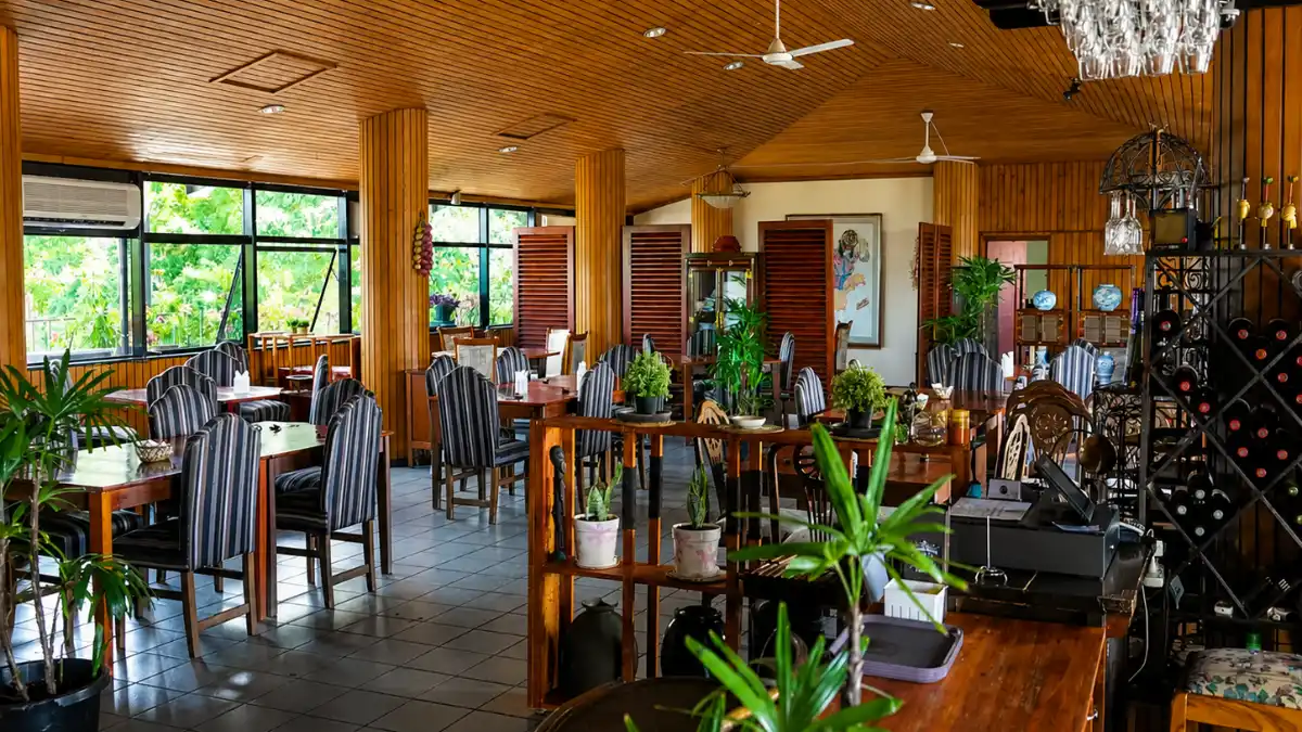 Dining room at Paradiso Restaurant & Bar in Suva, with wooden tables, striped chairs and a bar.