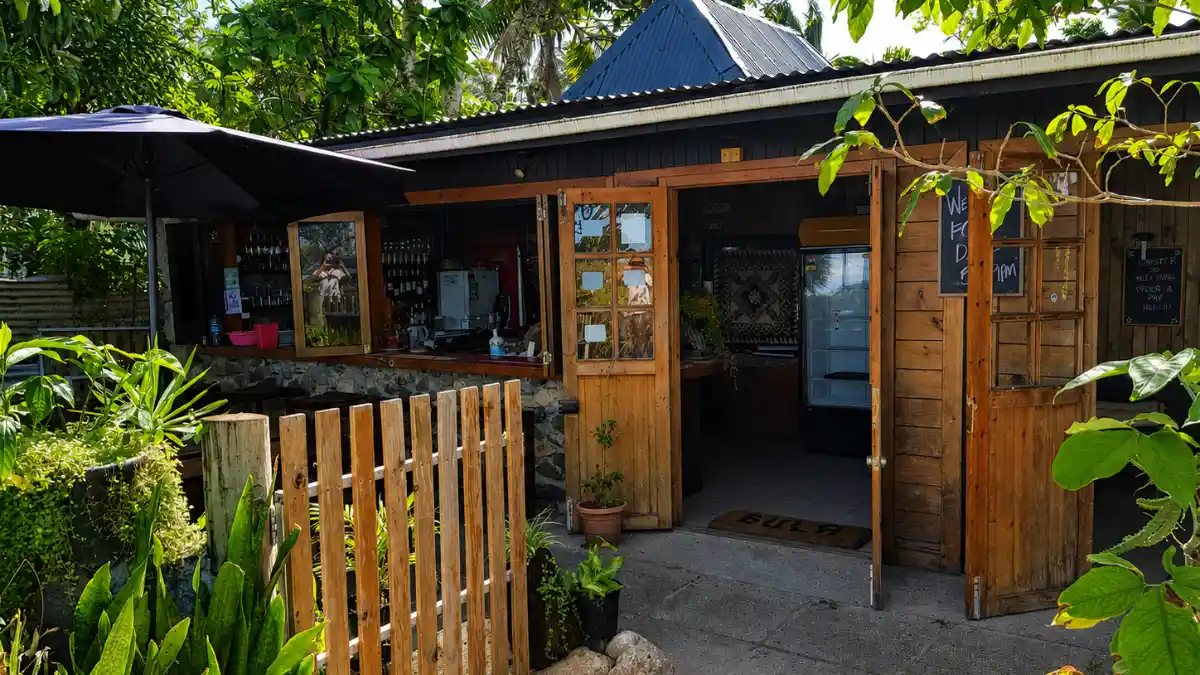 Wooden entrance to Beach Bar & Grill in Korotogo, Fiji, framed by tropical greenery