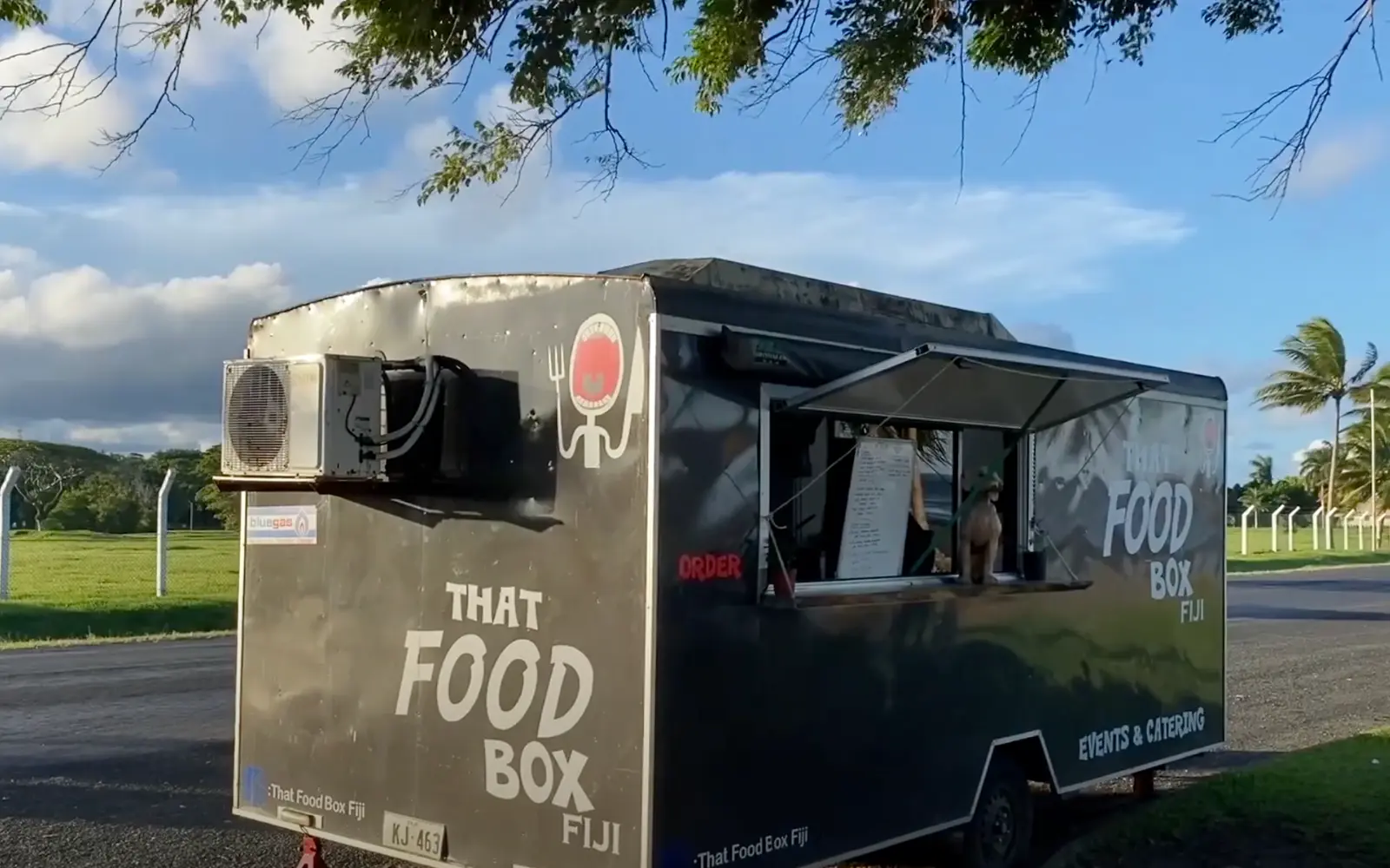 Locals grilling marinated meats over open flames at a street BBQ stall in Suva, Fiji.