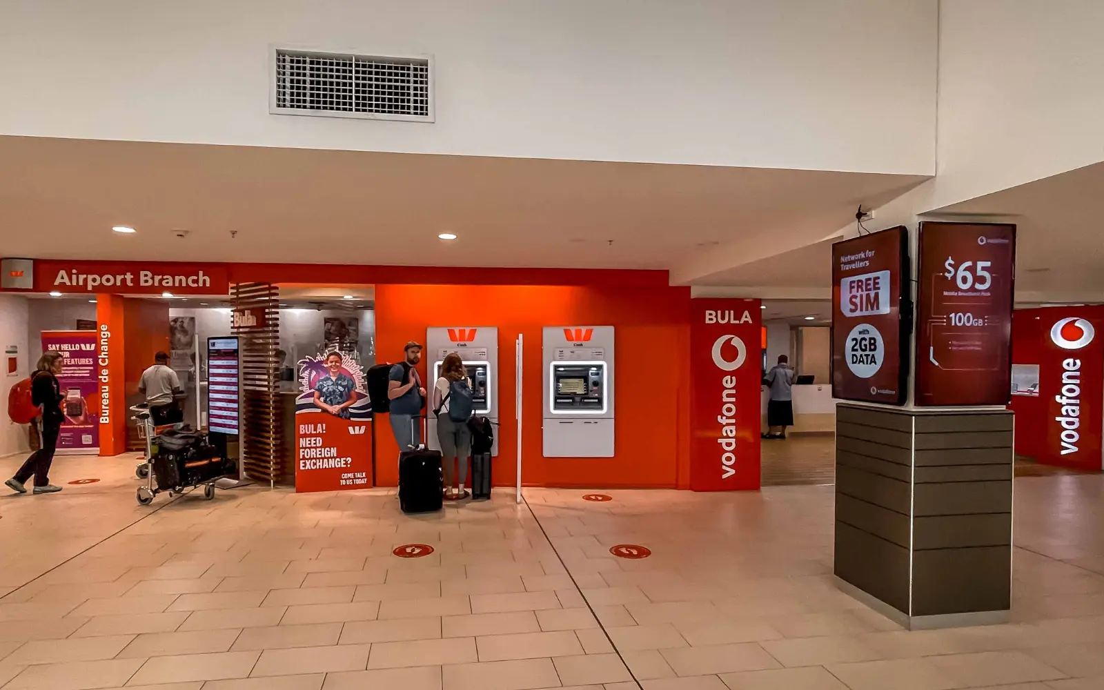 Close-up of a hand inserting a local SIM card (e.g., Vodafone or Digicel logo visible) into a smartphone.
