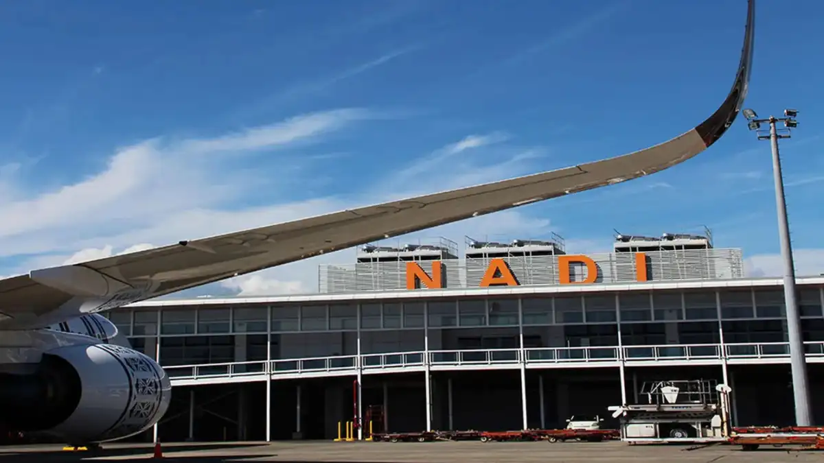 Aircraft wing and terminal building with orange NADI letters at Nadi International Airport, Fiji