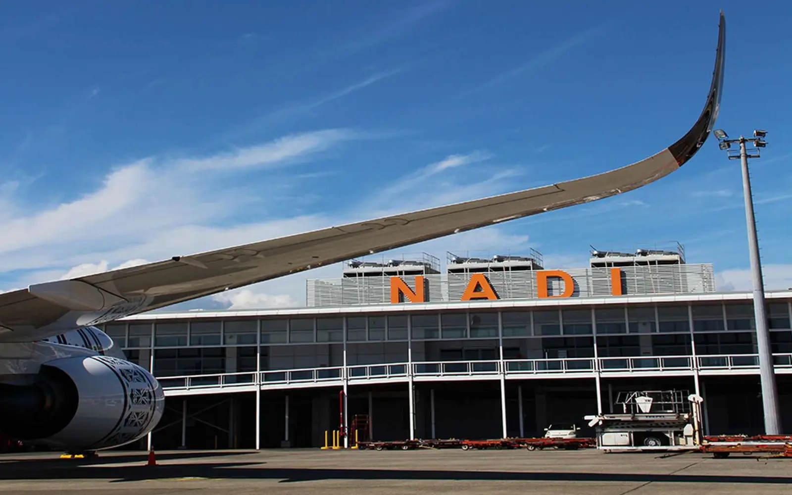 A shared shuttle bus waiting outside Nadi International Airport in Fiji, ready to transport travelers to their hotels.