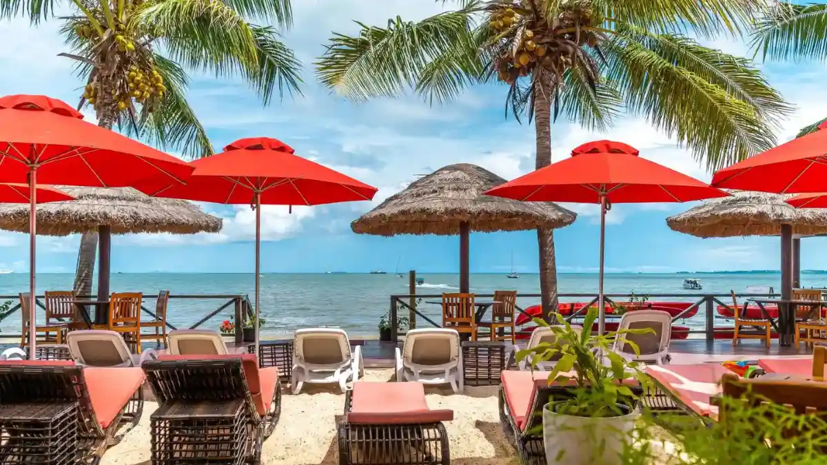 Beachfront seating under red umbrellas and coconut palms beside the sea in Fiji