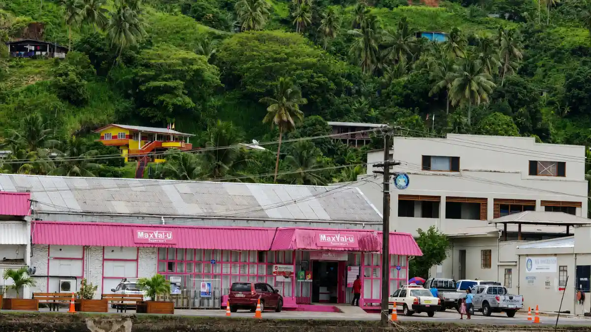 Pink MaxVal-u supermarket on the Savusavu waterfront below a green palm-covered hillside