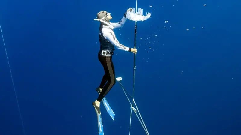 Free diver gliding above coral gardens with fish schools in Savusavu channel waters