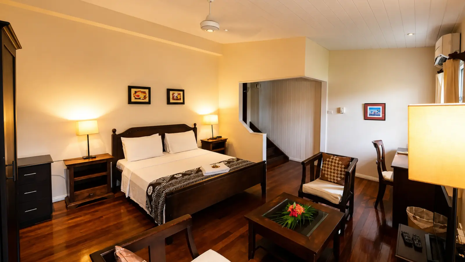 Boutique room at Five Princes Hotel in Suva with a queen bed, polished timber floor, armchairs and a writing desk.