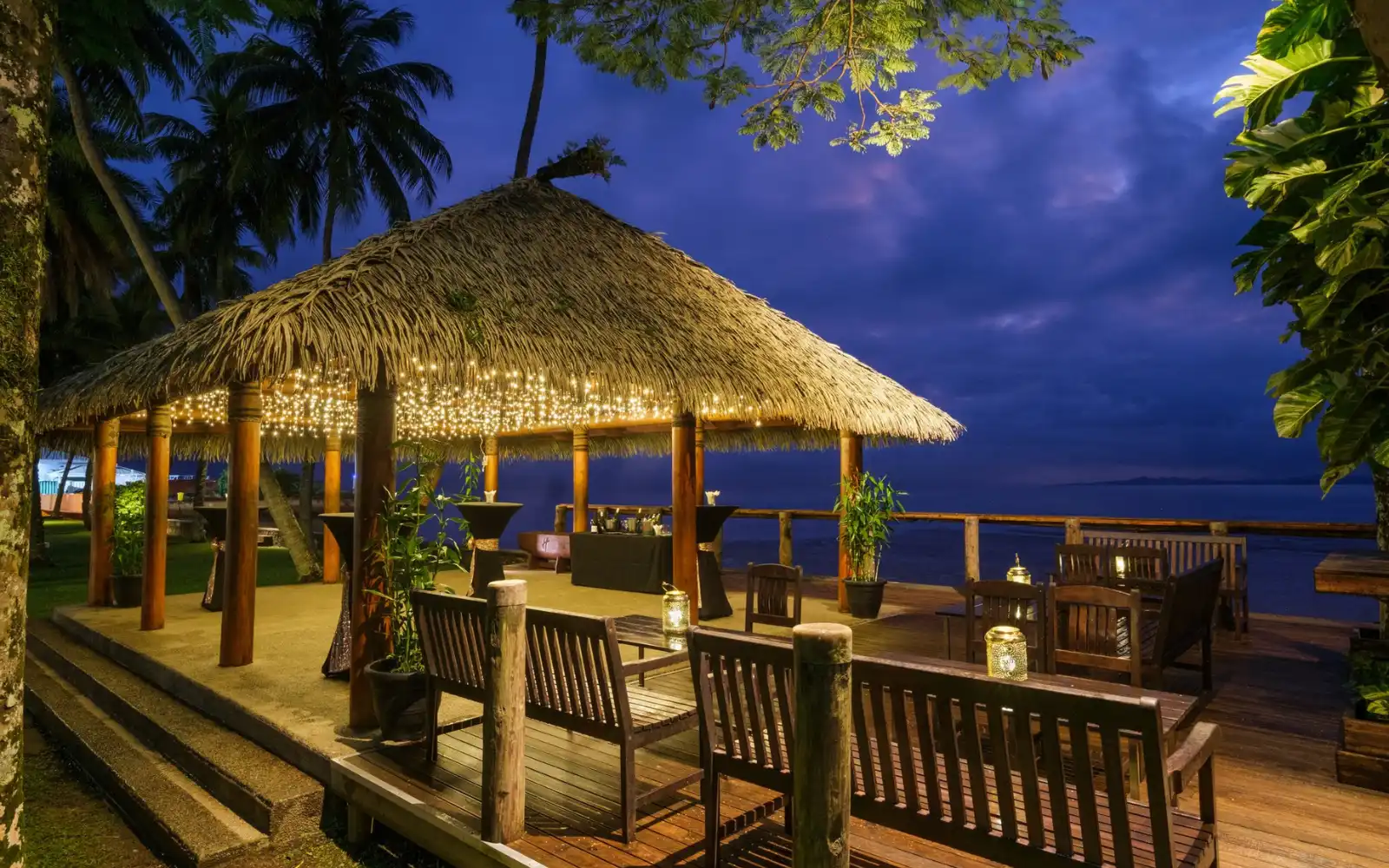 Outdoor swimming pool at Holiday Inn Suva with clear blue water, sun loungers, and the Suva harbor in the background.