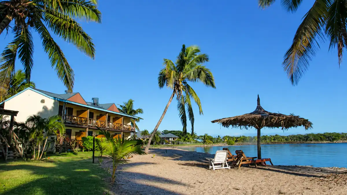 Fijian-style timber bures and palm trees beside the beachfront at Club Fiji Resort in Nadi.