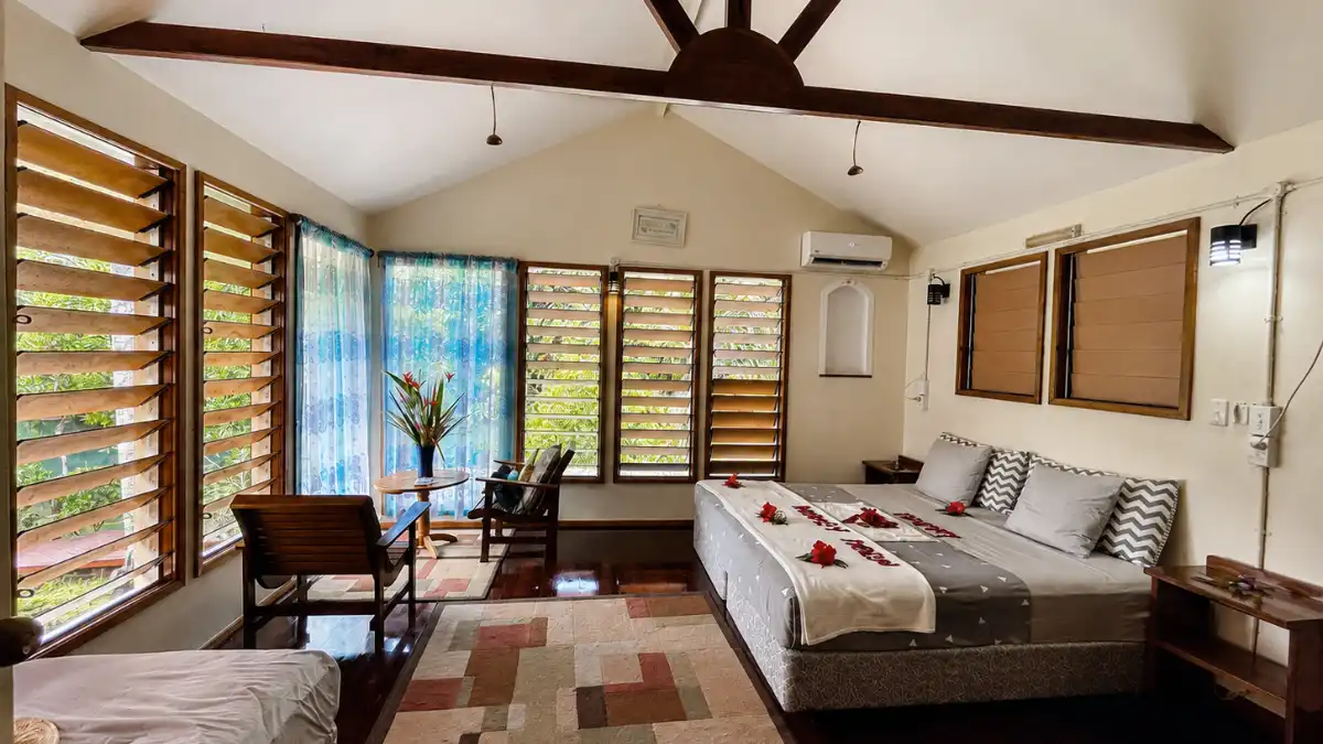 Interior of the Kingfisher bungalow at Salt Lake Lodge with a king bed and windows facing tropical greenery