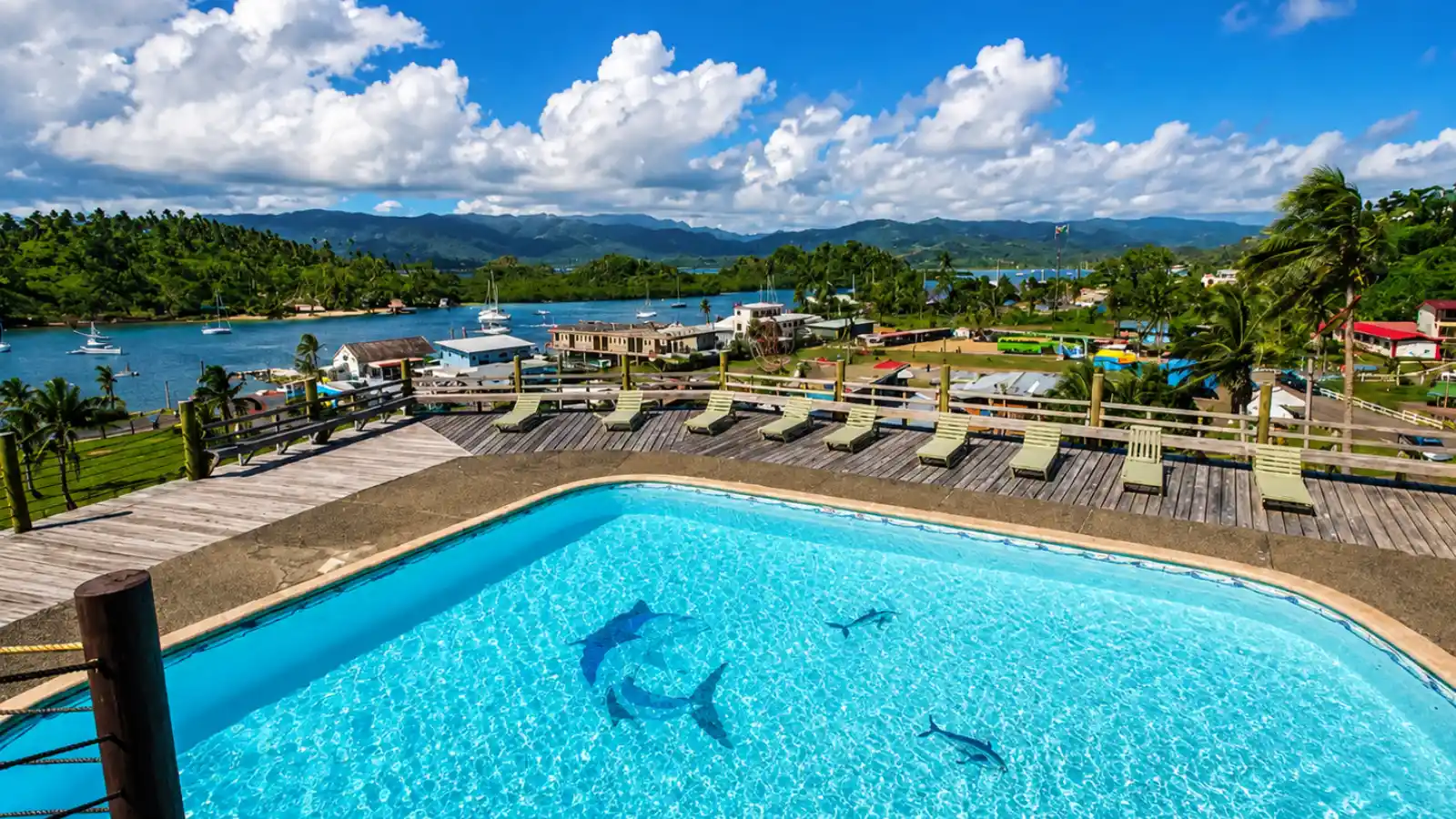 Swimming pool deck above Savusavu Bay with boats and green mountains in the distance