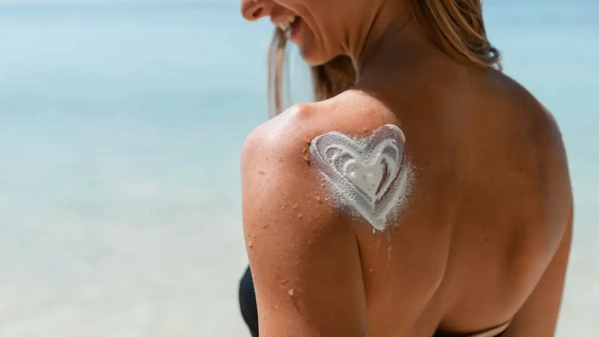 A traveler on a tropical beach with sunscreen drawn in a heart shape on their back