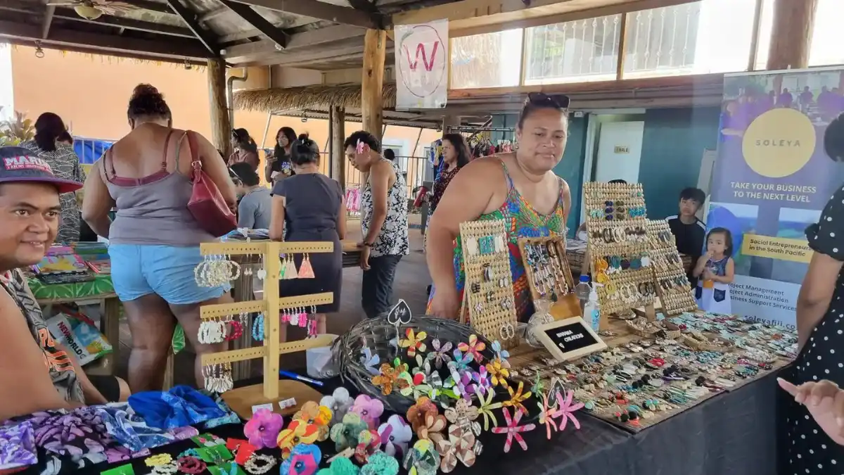 Women displaying handwoven baskets, mats and other locally made crafts at a market stall in Fiji