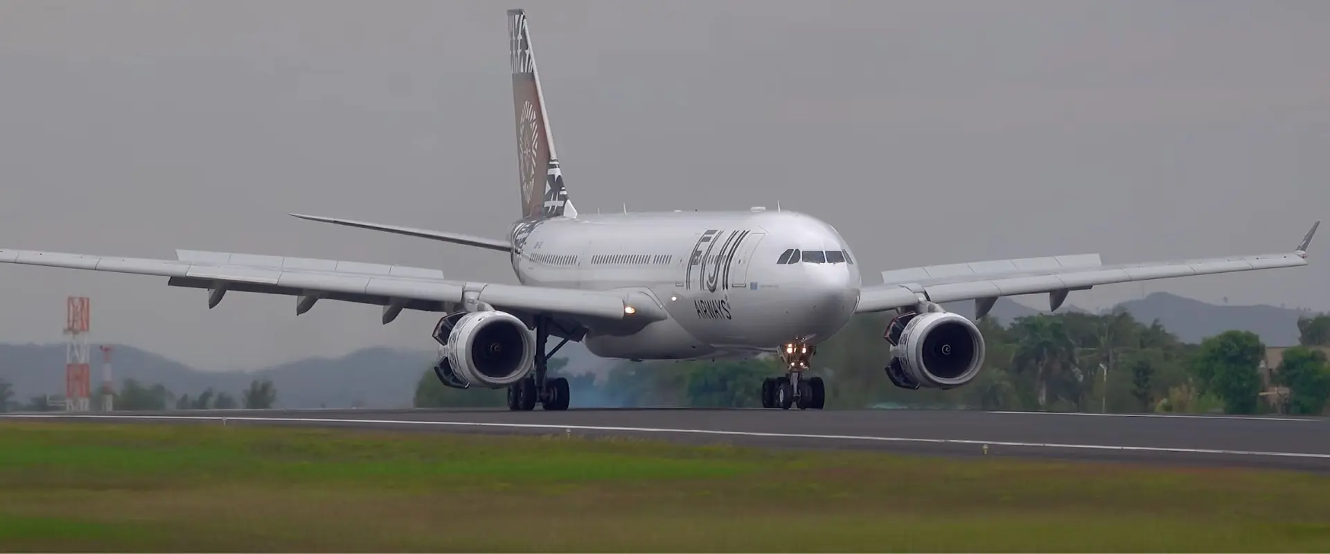 Fiji Airways airplane on the runway at Nadi International Airport with palm trees in the background