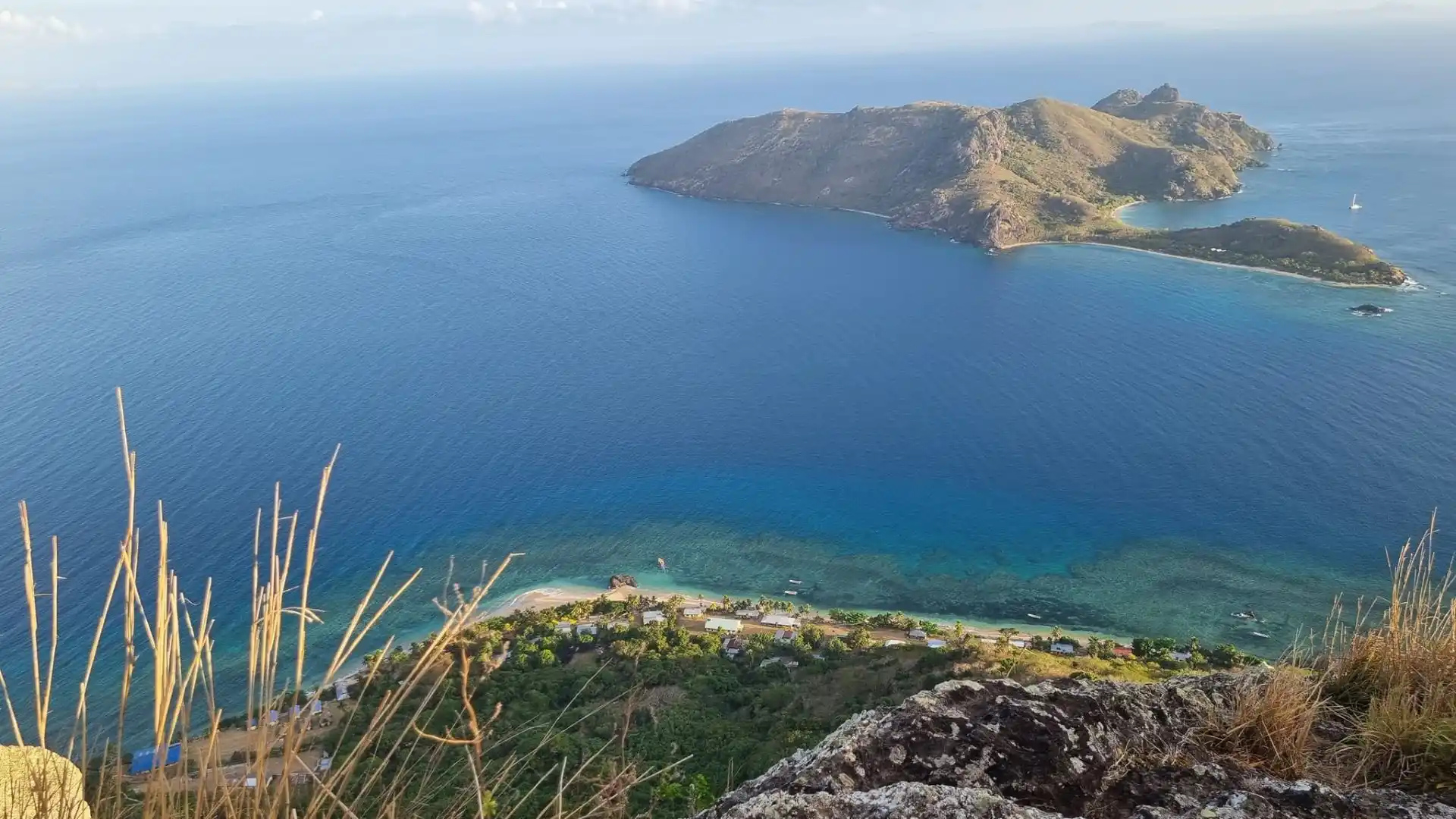 Panoramic view of Wayalailai Island's white sand beaches with dramatic volcanic peaks in the background