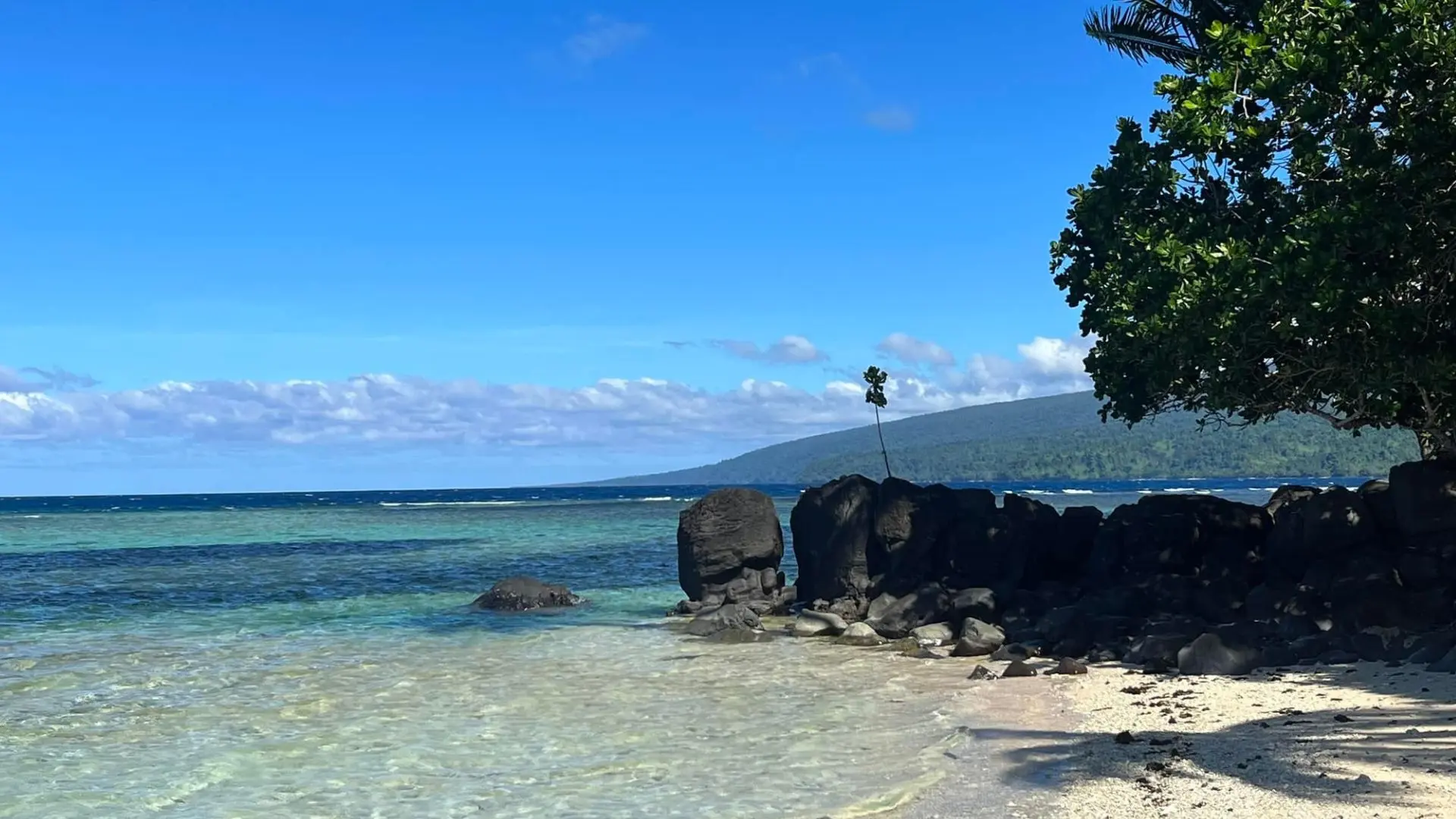 Dramatic black sand coastline and pristine waterfall at Lavena Coastal Walk, Taveuni